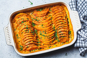 Roasted sweet potato gratin with parsley in ceramic pan. Vegan healthy recipe concept.