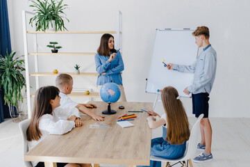 A teacher and students of different ages at a geography lesson. The student answers by standing...
