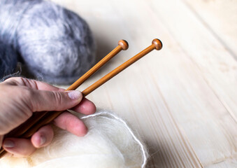 Close-up of an elderly woman's hand holding knitting needles.