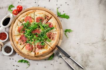 Fresh pizza with meat and ham on the concrete background