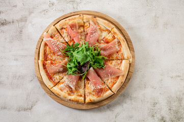 Fresh hot pizza with a ham on the concrete background