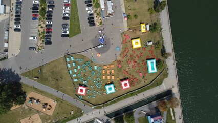 Aerial top view of colorful tents on a grass field, with cars in the parking lot