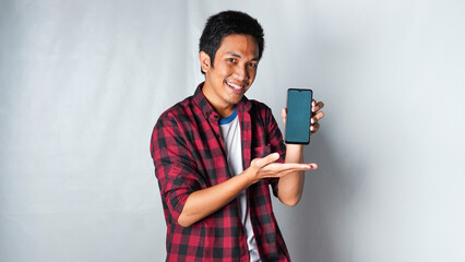 Adult asian man wearing red flannel tshirt holding him phone with smile face excited isolated white...