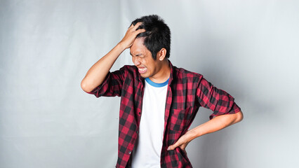 Asian man hitting his head, suffering from migraine headache or regret gesture, against white background