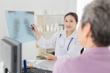 Fototapeta premium Asian doctor looking patient film, she talk with patient about disease, broken bone treatment, tuberculosis screening