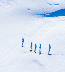 Walking shadows - hikers seen from above with their shadows like waking in the snow
