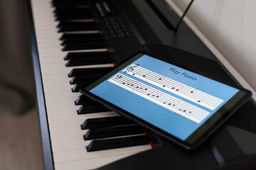 Piano keys, music notebook and tablet on the background of the wall. Mock up for online piano courses.