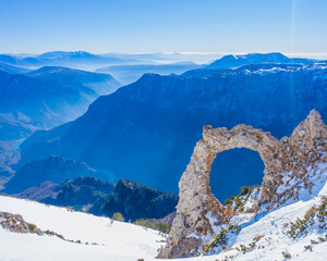 A hole in the rock with a beautiful view of the mountains and the river in the valley - Hajduk Gates on Cvrsnica Mountain with snow in the winter