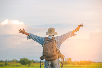 A tourist man raising hands with backpack in the countryside 