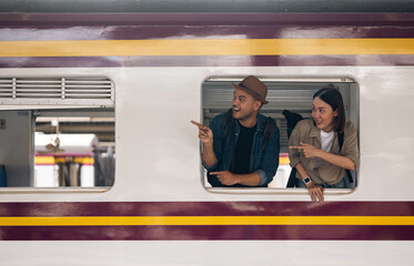 Couple asian traveller with bag on honeymoon travel by train Sticking head outta the window. Happy...