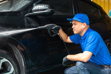 Man worker washing car service. Car wash cleaning station high pressure water. Employees clean a vehicle professionally.
