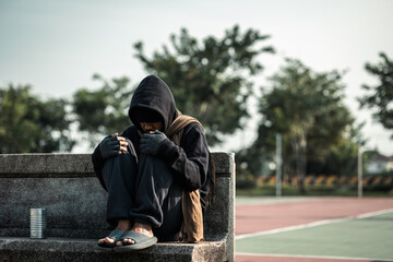 Poor tired stressed depressed hungry homeless man in the shadow city. Homeless man sitting on the...