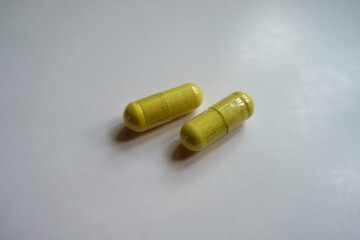 Close shot of two greenish yellow capsules of quercetin dietary supplement