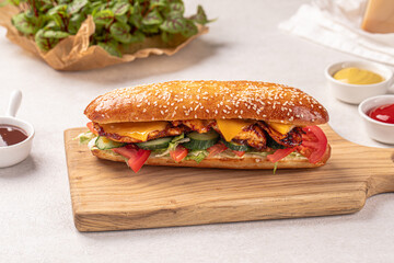 Chicken baguette sanwich with vegetables on cutting board