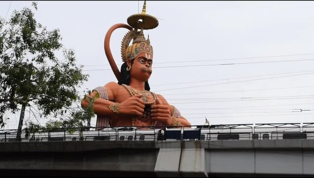 Delhi metro train passing near big statue of Lord Hanuman situated near Karol Bagh, Delhi, India, Lord Hanuman big statue touching sky