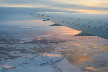 Airplane view of a city in the Arctic. Aircraft wing. Top view of the city of Anadyr, located on...