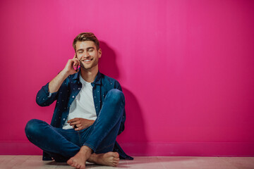 Portrait of a happy man using smartphone isolated over pink background.