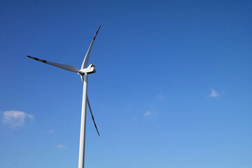 Turbina wiatrowa na tle niebieskiego nieba.