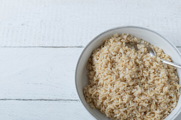 Cooked brown rice in a bowl on white background