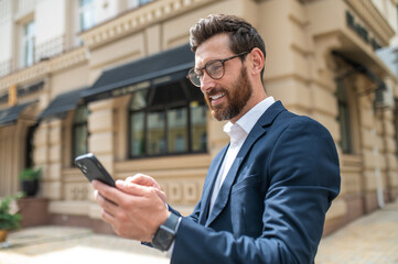 Man in elegant suit with a phone in hands in the street