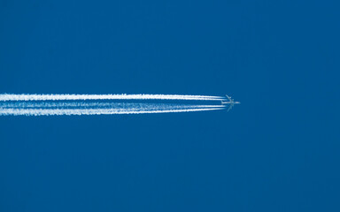 Airplane with a long reverse trail in the blue sky