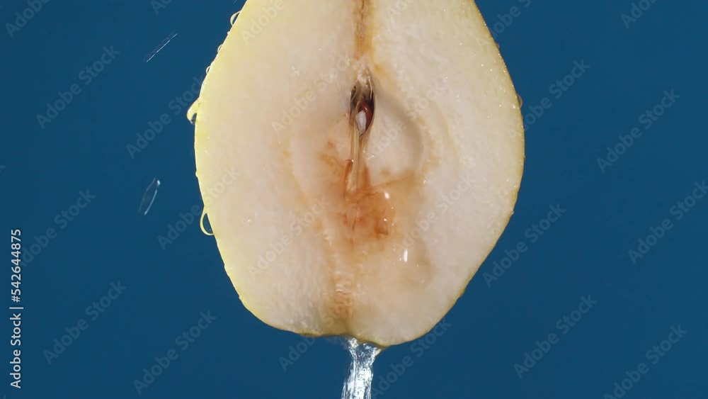 Poster yellow half pear on a blue dark background with drops of water rolling down the pear and flowing spl