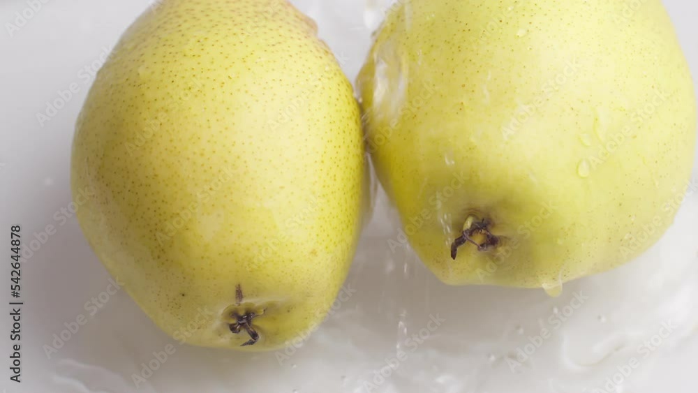 Poster yellow pear on a blue dark background with drops of water rolling down the pear and flowing splashin