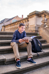 Joyous teen with a book sitting on the stairs