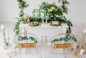 Wedding. Composition. On a wooden white table with serving dishes and glasses decorated with green flowers on a white background texture

