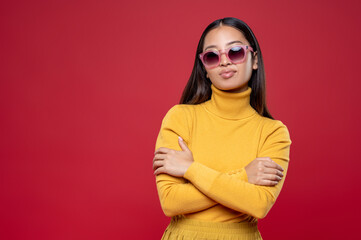 Stylish young woman in sunglasses standing against the wall