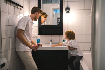 Dad and son in the batheroom getting ther morning procedures done