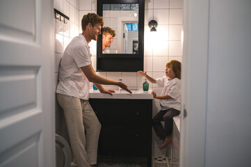 Naklejka na ściany i meble Cute little boy and his dad washing hands in the bathroom