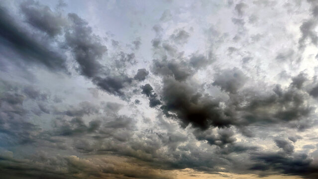 Cloudy sky with stormy clouds. Low cumulus clouds of various shapes cover almost the entire sky. They are at different heights and have different colors of white, light gray and dark blue.