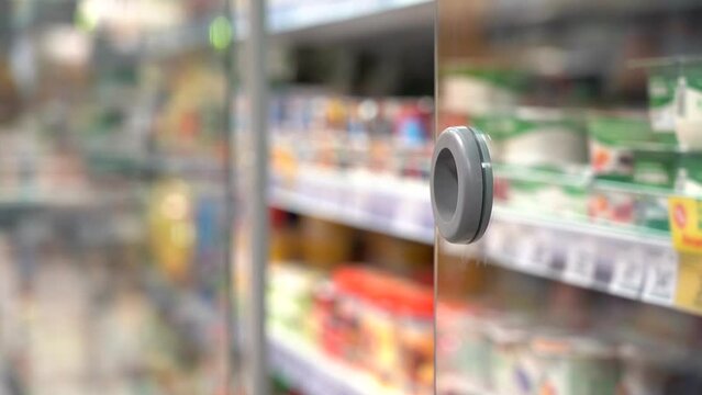 Senior couple at choosing products at the supermarket. A Shopper Opens the Refrigerator in the Store.