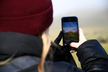 person taking a photo of a rainbow with phone