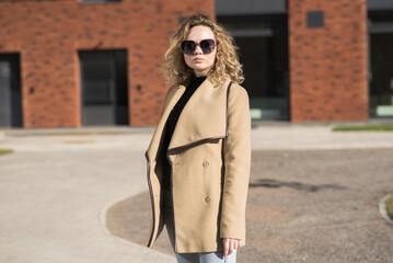 Obraz premium Portrait of a young Caucasian girl in a coat and sunglasses in the city on an autumn day.