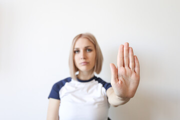 Girl holding a stop signal hand on a light background