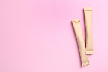 Beige sticks of sugar on pink background, flat lay. Space for text