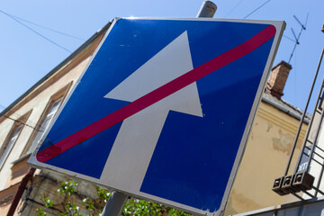 One way street road sign, White arrow in blue background, crossed out of red line on autumn foliage...