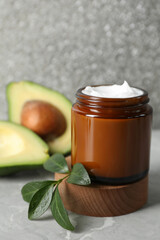 Jar of face cream and avocado on marble table