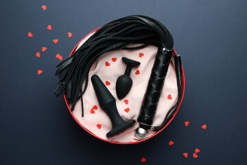 Gift box with different sex toy on dark blue background, flat lay