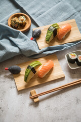 Lachs Avocado Sushi als Nigiri, Maki, roh und knusprig frittiert auf Holz Teller mit Soja Soße in...
