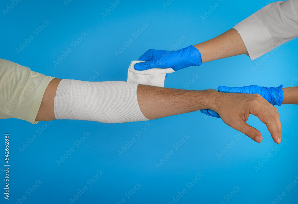 Canvas Prints Doctor applying medical bandage onto patient's hand on light blue background, closeup