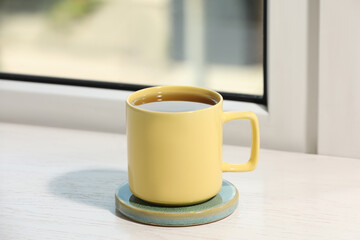 Yellow cup of tea on wooden window sill