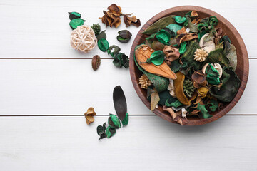 Aromatic potpourri of dried flowers in bowl on white wooden table, flat lay. Space for text