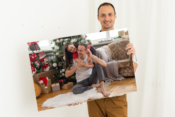a man holds a Christmas photo on a photo canvas