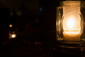 Votive candle burning at a cemetery at night
