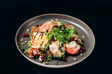Traditional Salad of arugula and ham with the addition of green apples, olives and spices on a white plate in the composition with fresh bread. Horizontal top view.