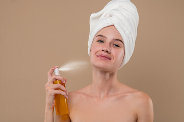 Young girl spraying hydrating mist on her face