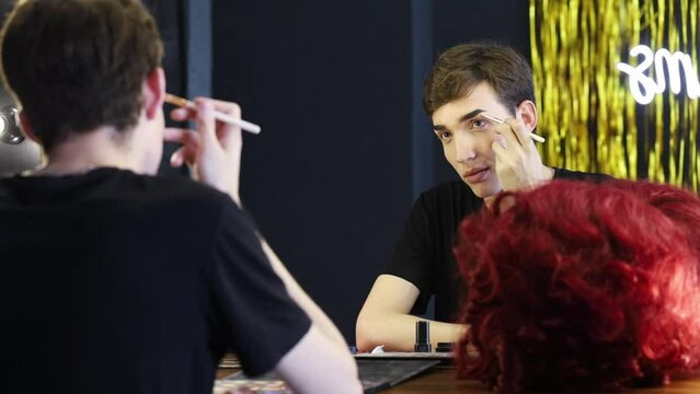 Young performer looking in mirror applying make up